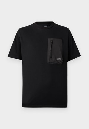 T-shirt noir à manches courtes avec une grande poche rectangulaire zippée sur le côté gauche de la poitrine, comportant une petite étiquette logo blanche.