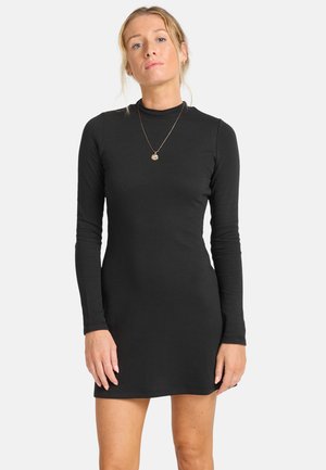 Robe noire à manches longues côtelées avec une silhouette ajustée, dotée d'un col haut et d'une longueur mi-cuisse. Design minimaliste sans motifs.