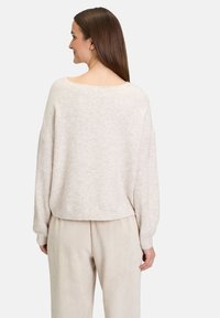 Hellbeige, kurz geschnittene Sweater mit weitem Ausschnitt und herunterhängenden Schultern, aus weichem, strukturiertem Stoff. Kombiniert mit passenden gerippten Hosen.