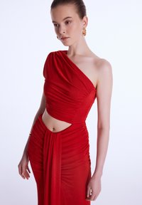 Rød one-shoulder kjole med rynket tekstur og udskæring i taljen, der har en elegant drapering og glat stof.