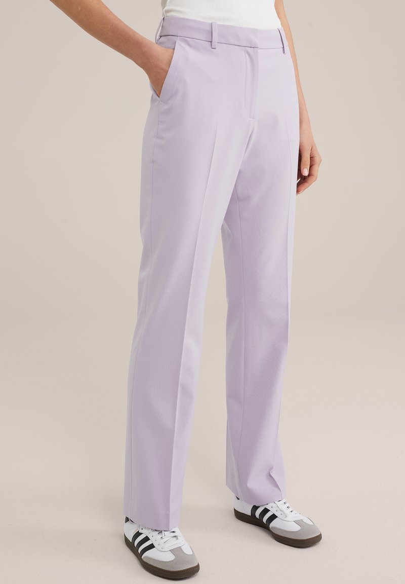 Helle lila maßgeschneiderte Hose mit Seitentaschen, geradem Bein und glatter Textur, kombiniert mit weißen und grauen Sneakers.
