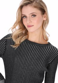 Maglione a coste nero e grigio con scollo ampio e tessitura morbida, caratterizzato da strisce verticali e un design aderente.