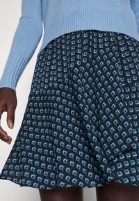 Blauwe rok met een geometrisch patroon in tinten blauw en zwart, met een uitlopende vorm en zachte stoffen textuur.