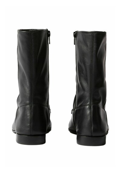 Botas de cuero negro hasta el tobillo con una textura suave, cierre de cremallera y un diseño elegante y ajustado. Tacón plano y detalles de costura mínimos.