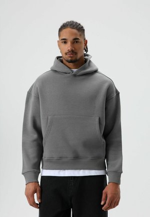 Grijze hoodie gemaakt van zachte stof, voorzien van een voorzak, capuchon met trekkoord en geribde boorden met een licht oversized pasvorm.