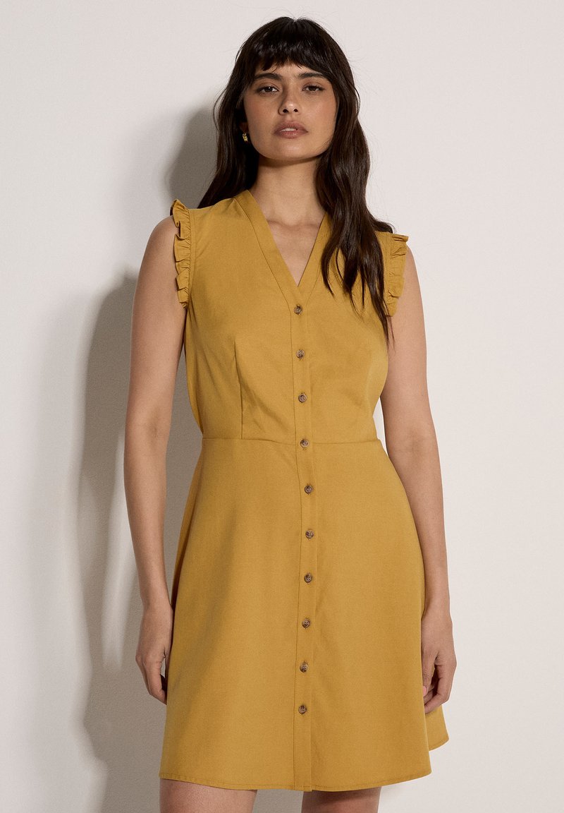 Robe à manches courtes jaune moutarde avec un décolleté en V, des détails volantés aux épaules, et une fermeture boutonnée sur le devant, dotée d'une jupe évasée.