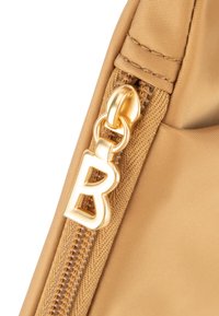 Gul handväskas dragkedja med framträdande gyllene detaljer. Materialet är slät tyg med fin textur. Utrustad med en stiliserad bokstav "B" charm.