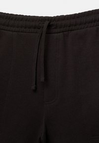 Sorte sweatpants med elastisk talje, snørrelukning og sidelommer med subtile syningsdetaljer. Blød stoftekstur.