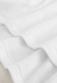 White textured fabric with a soft, ribbed surface. Features smooth, rounded edges with subtle stitching detail.