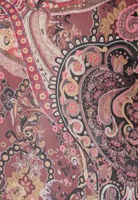 Πολύπλοκο ύφασμα με σχέδιο paisley σε ροζ, μαύρο και μπεζ, λουλουδένια μοτίβα και κυματιστά διακοσμητικά στοιχεία σε απαλό ροζ φόντο.