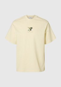 Jasnożółta bawełniana koszulka z krótkim rękawem, z małym graficznym nadrukiem klucza i aparatu na środku.