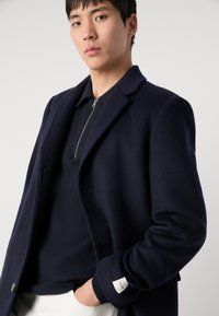 Marineblauwe wollen mix jas met een op maat gemaakte ontwerpelementen, voorzien van een ingevouwen kraag, knoopsluiting en een groene gebreide binnenlaag met rits.