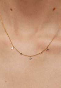 Collar de cadena de oro con cinco piedras geométricas de colores: dos azules, una rosa y dos transparentes, dispuestas en un diseño delicado.