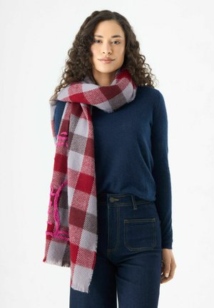Rot- und graues kariertes Tuch aus weichem Stoff, mit fransigen Kanten und pinkfarbenen gestickten Akzenten, über einem dunklen Pullover drapiert.