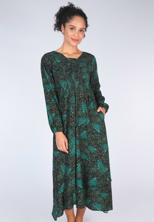 Langärmliges, knöchellanges Kleid aus schwarzem Stoff mit grünem und braunem Blättermuster; hat einen bescheidenen Ausschnitt und Seitentaschen.