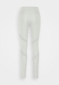 Leggings gris clair avec une texture lisse, une taille haute et des panneaux en maille diagonale pour la respirabilité sur les côtés.