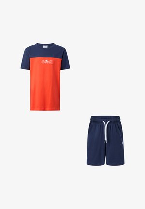 Camisa de manga corta con parte superior azul marino y parte inferior naranja, logo blanco de "Champion", combinada con pantalones cortos azul marino con cordón.