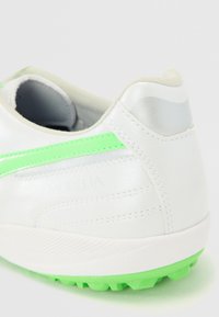 Pantofii de fotbal albi, cu un finisaj din piele texturată, fâșie de accent verde și talpă verde contrastantă. Detalii argintii pe călcâi.