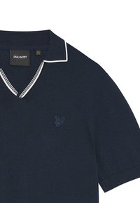 Polo shirt blu navy realizzato in tessuto morbido, con scollo a V, colletto con bordi bianchi e un piccolo logo ricamato blu sul petto.