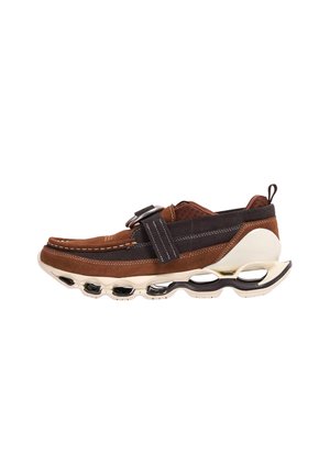 Sneaker in camoscio marrone e nero con suola bianca unica caratterizzata da strutture di supporto scavizzate e una fascia larga sulla parte superiore.