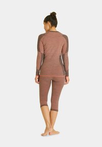 Long-sleeve, fitted top and capri-length leggings in a textured, reddish-brown fabric with dark brown accents and flat seams.