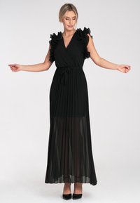 Schwarzes Maxikleid mit plissiertem Rock, gerüschten kurzen Ärmeln, verstellbarem Taillengürtel und durchscheinendem Material. Mit tiefem V-Ausschnitt.