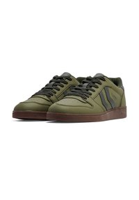 Green sneakers with a smooth leather upper, textured accents, dark grey laces, and a brown rubber sole feature side stripes and perforations.
