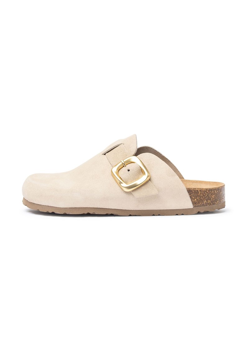 Mocassin en suédine beige avec un accent de boucle dorée, semelle intérieure légère en liège et semelle en caoutchouc texturé. Design classique à enfiler pour le confort.