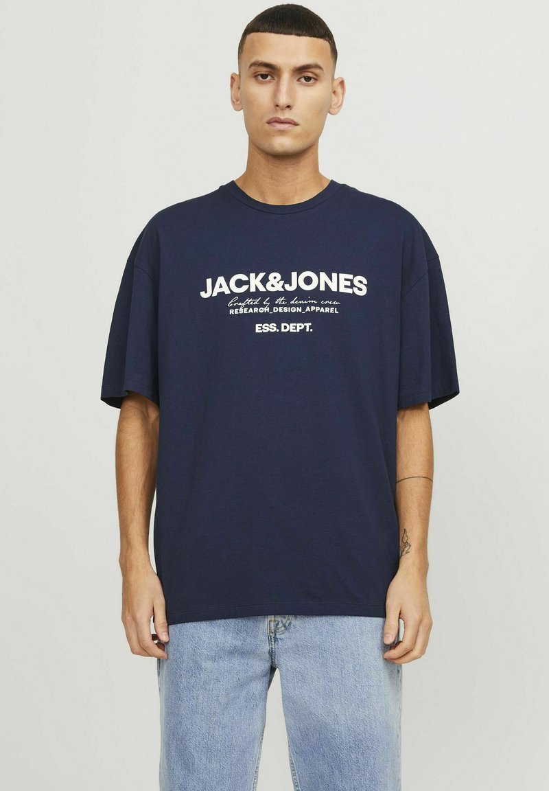 Camiseta de algodón de gran tamaño en azul marino con un diseño de logotipo y texto en blanco en el pecho, cuello redondo y mangas cortas.