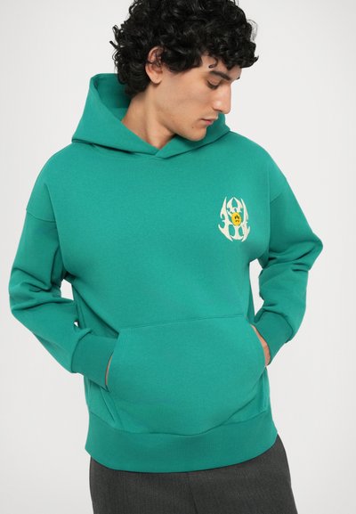 Felpa turchese con tasca frontale, cappuccio regolabile con cordino e logo grafico che presenta un volto e design astratti sul petto sinistro.