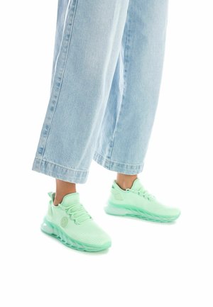 Zapatillas de color verde menta claro con parte superior de malla, patrones texturizados y una suela gruesa y translúcida. Combinadas con pantalones de mezclilla sueltos de color azul claro.