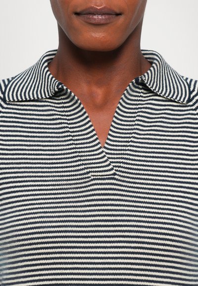 Striped knit polo shirt featuring navy and cream lines, a classic collar, and a half-button placket. Textured fabric with a relaxed fit.