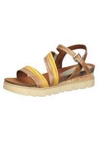 Sandale à lanières marron et jaune avec un talon en liège et une semelle en caoutchouc, présentant des motifs texturés et une bride de cheville réglable.