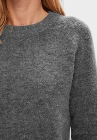 Harmaa neulepaita, jossa on pyöreä pääntie, pehmeä rakenne ja hieman pörröinen ulkonäkö; siinä on resorit hihansuiden ja helman kohdalla.