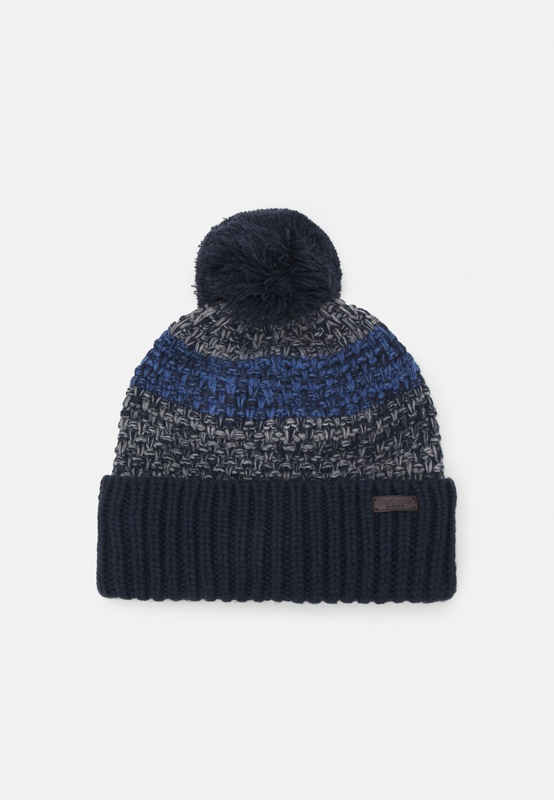 Knit beanie hat featuring a pom-pom on top, dark blue and grey woven pattern, and a ribbed dark blue cuff with a label.