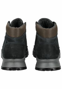 Botas de cuero negras hasta el tobillo con suelas de goma grises. Cuentan con un cuello de textil marrón texturizado y detalles de costura sutiles.