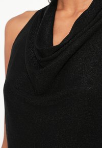 Črni top brez rokavov s spuščeno ovratnico v stilu kape z metalik sijajem, gladke teksture in oprijetega kroja.