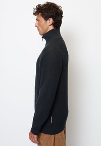 Dark gray, zip-up sweater with a high collar, textured knit pattern, long sleeves, and side slits at the hem. Casual fit.