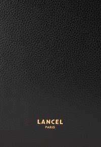 Portefeuille en cuir noir texturé, avec un logo doré en relief "LANCEL PARIS" en bas. Surface lisse avec un motif de grain visible.