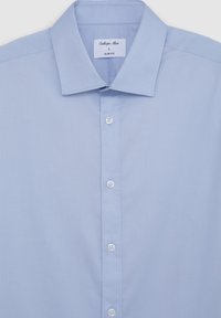 Camicia azzurro chiaro slim-fit con colletto a punta, bottoni bianchi e tessuto testurizzato. L'etichetta all'interno del colletto indica la taglia L.
