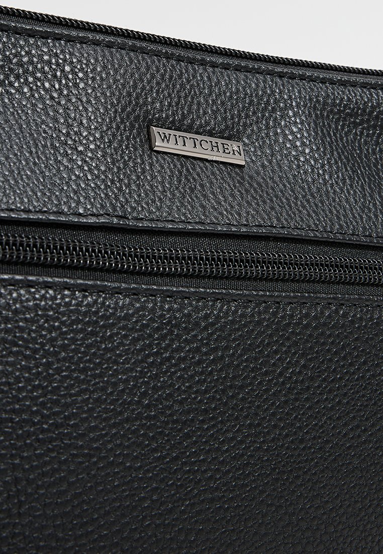 Schwarze, strukturierte Lederhandtasche mit einem Reißverschluss und einem silbernen "WITTCHEN"-Logoschild. Sie zeichnet sich durch eine glatte Oberfläche und feine Nahtdetails aus.