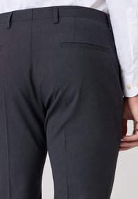 Kolen-grijze op maat gemaakte broeken met een gladde textuur, voorzien van twee achterzakken en een recht snit, aangevuld met een wit overhemd.