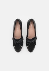 Ballerine nere con finitura in pelle liscia, sovrapposizione in suede frangiato e un fiocco decorativo. Presentano dettagli in tono argento sul fiocco.