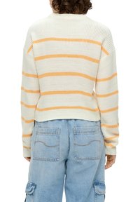 Cremiger Strickpullover mit orangefarbenen horizontalen Streifen, geripptem Rundhalsausschnitt und cropped Saum. Kombiniert mit hellblauen, lockeren Cargo-Hosen mit Taschen.