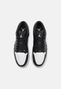 Black and white leather sneakers featuring a perforated toe box, flat laces, and a subtle logo on the tongue and sides.