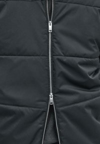 Giacca imbottita nera con cerniera argento a tutta lunghezza, tessuto liscio e motivo trapuntato sul corpo.