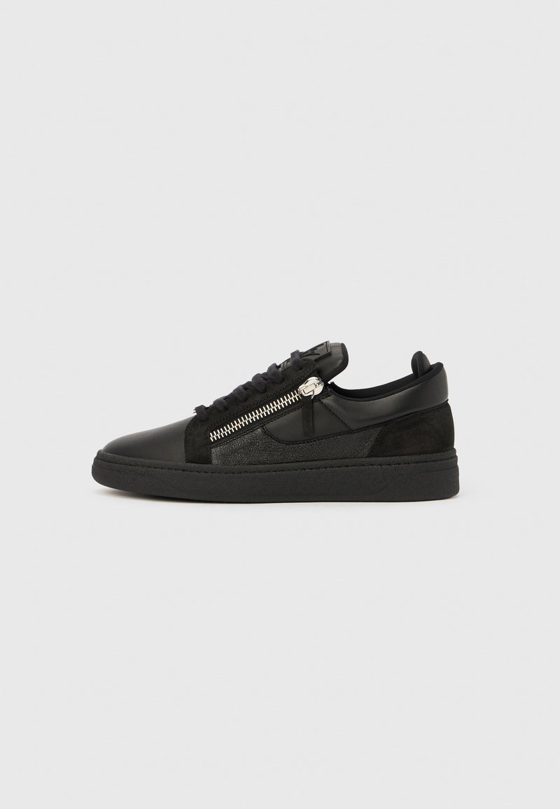 Black low-top sneaker with suede and leather panels, lace-up front, and a silver side zipper on a plain background.