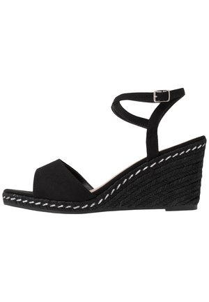 Sort kile-sandal med åben tå, ankelrem med spænde og tekstureret fletplatform med hvide syninger.