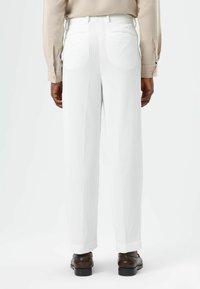 Witte ribbroeken met een comfortabele pasvorm, voorzien van een gladde tailleband en zijzakken, gecombineerd met bruine nette schoenen.