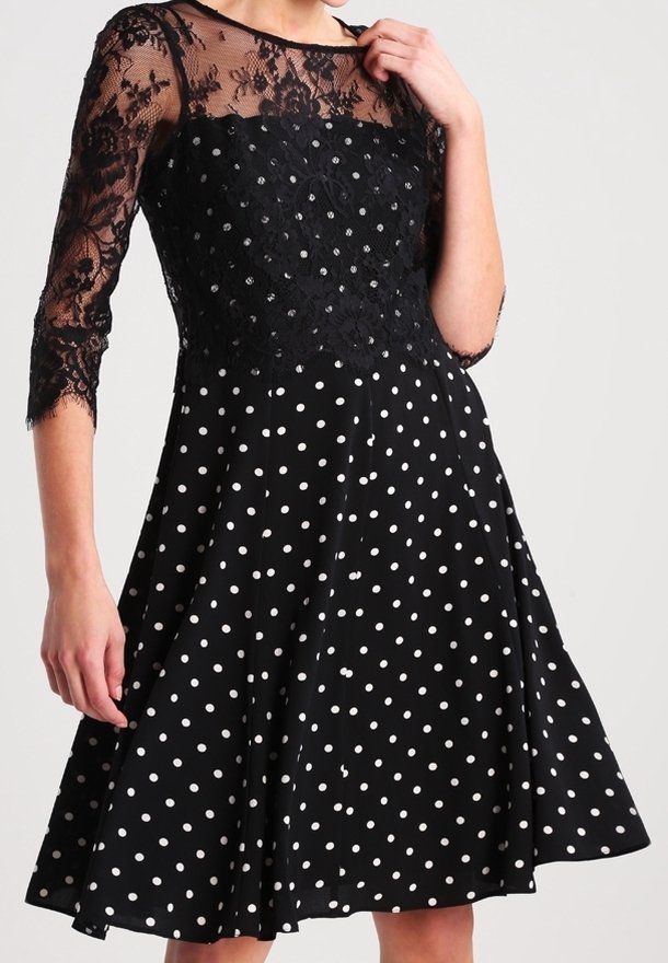 Svart klänning med spetsliv och trekvartslånga ärmar, med ett prickigt mönster. Urtjockad kjol och texturerad spetsdetalj.